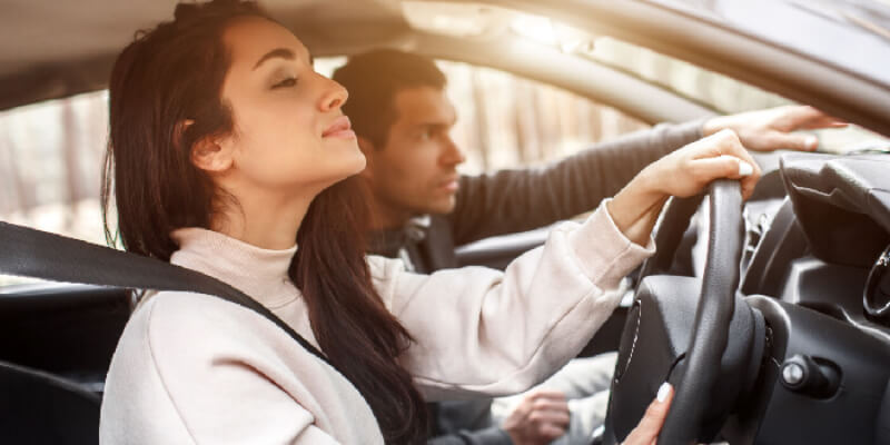 Instructor pointing over dashboard to guide learner driver
