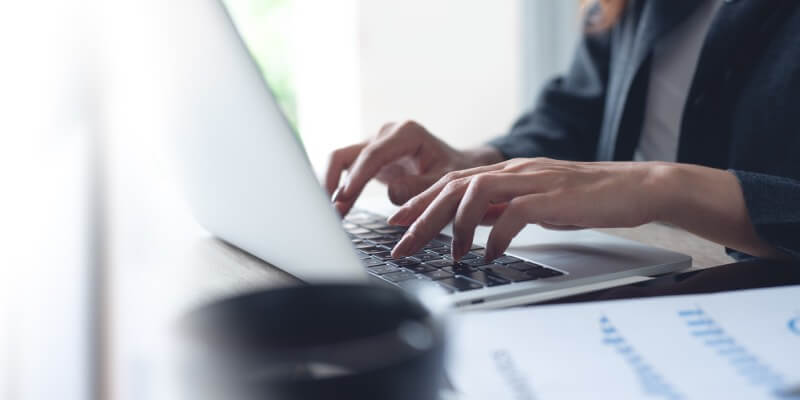 Both hands typing on a laptop