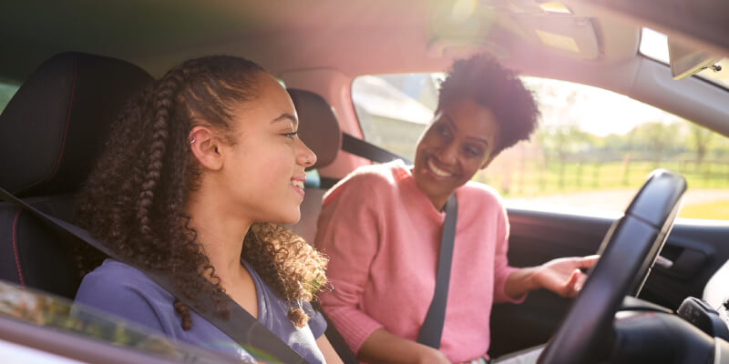 Two girls smiling at each other inside the car